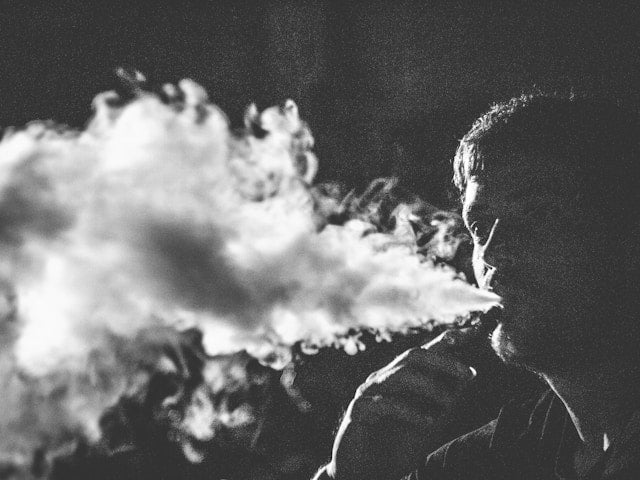 a man blowing a large vape cloud for how much nicotine is in a elf bar